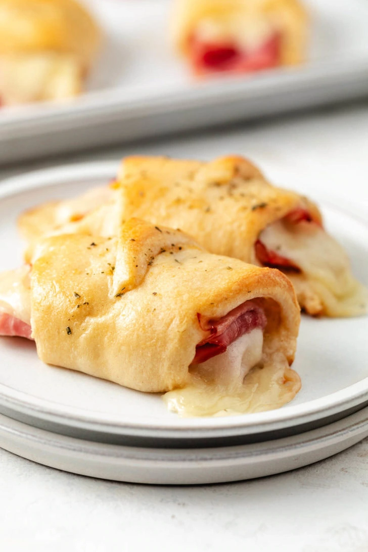 Close-up of two ham and cheese crescent rolls on a plate.