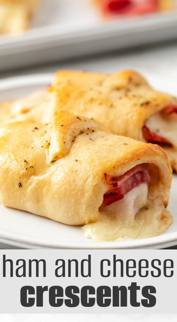 Two ham and cheese crescent roll ups on a plate.