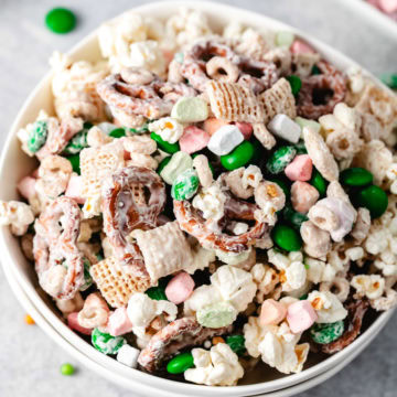 A festive snack mix with popcorn, pretzels, cereal, and colorful candies coated in vanilla melting wafers.