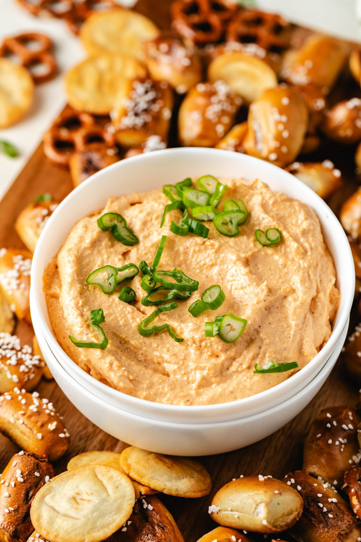 A creamy bowl of cheese spread with green onions on top.