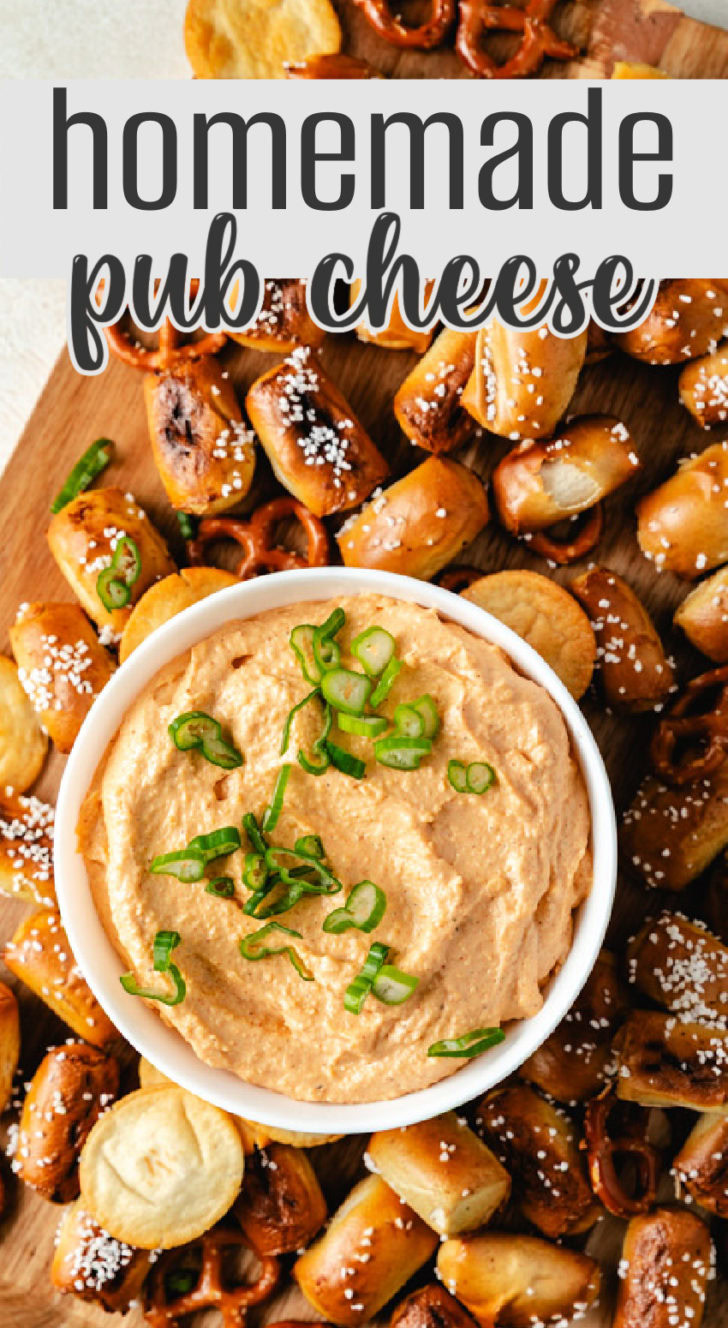 A top-down view of homemade pub cheese spread surrounded by soft pretzels and crackers on a wooden board.